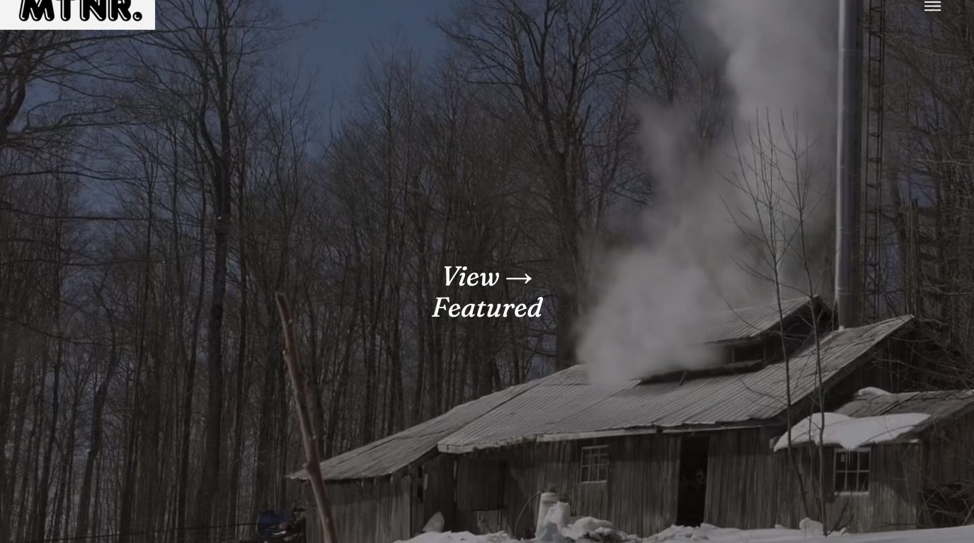 Still image of our motioneer.ca website with director reel playing showing billowing chimney smoke from a winter cabin.